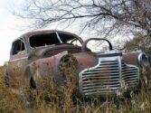 Old rusty broken down car in overgrown weeds
